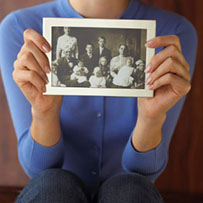 A woman holding a black and white photograph of her ancestors.