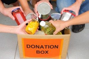 people donating canned goods to a donation box